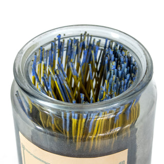 Close up of top of glass apothecary jar with blue tipped incense sticks