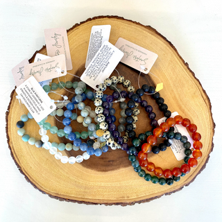 Several varieties of gemstone beaded bracelets on wooden backdrop.