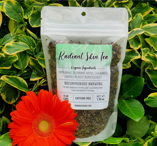 Radiant skin organic herbal tea in package, against foliage and flower background.